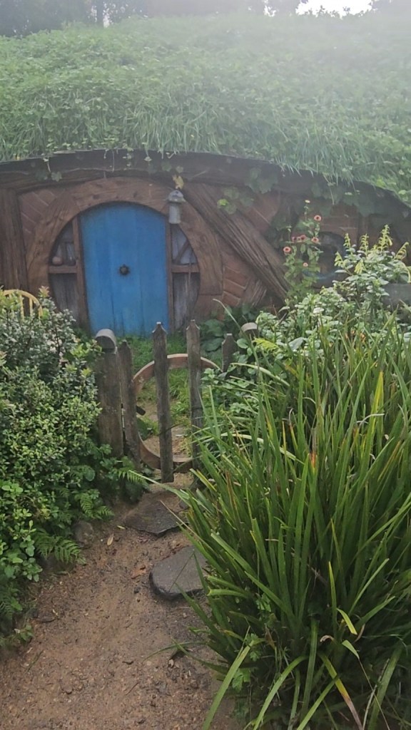 Blue hobbit door tucked into the green hillside at Hobbiton in New Zealand.