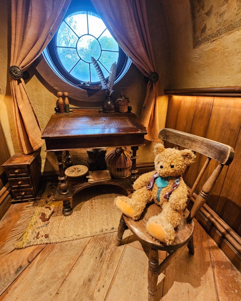 Patch sitting on a childs chari, by a desk in front of a round Hobbit window.